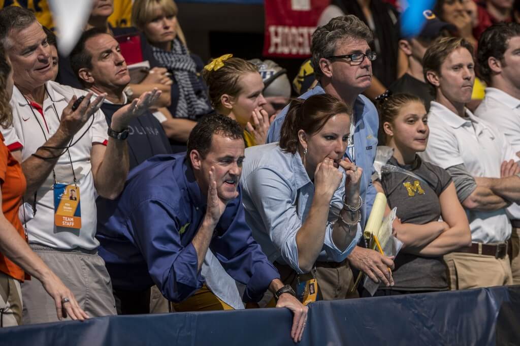 Michigan coaches and team cheering their swimmers.