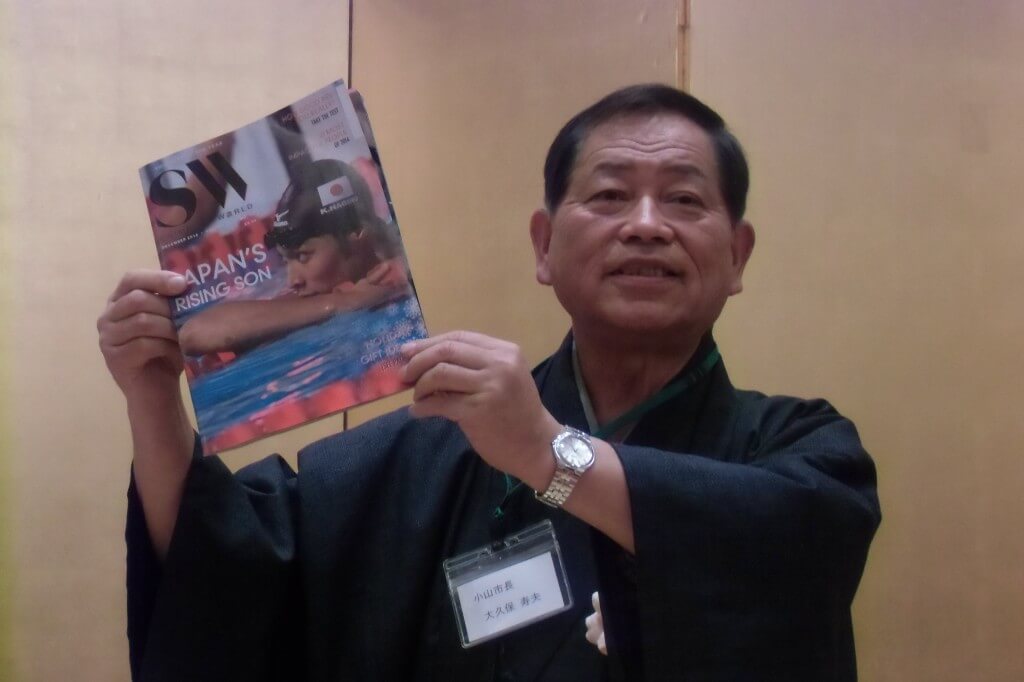 Toshio Okubo poses with Swimming World Magazine with Kosuke Hagino on cover