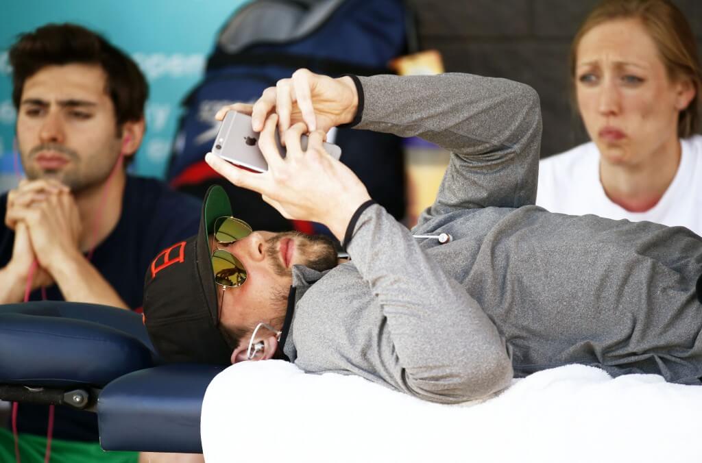 Apr 16, 2015; Mesa, AZ, USA; Michael Phelps looks at his iPhone as he receives a massage before the Men's 100 meter butterfly final during the 2015 Arena Pro Swim Series at the Skyline Aquatic Center. Mandatory Credit: Rob Schumacher/Arizona Republic via USA TODAY Sports