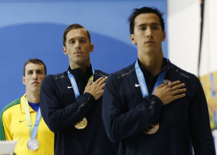 Jul 17, 2015; Toronto, Ontario, CAN; Nicholas Thoman of the United States (middle) and Eugene Godsoe of the United States (right) stand for the national anthem after the men's 100m backstroke final the 2015 Pan Am Games at Pan Am Aquatics UTS Centre and Field House. Mandatory Credit: Rob Schumacher-USA TODAY Sports