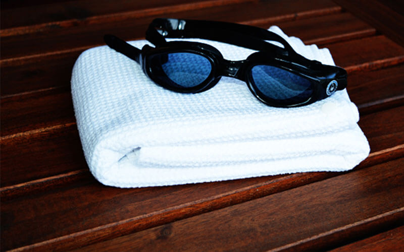 Snappy Towels are textured microfiber swim towels that are compact yet comfortable. Shown here folded with swimming goggles.