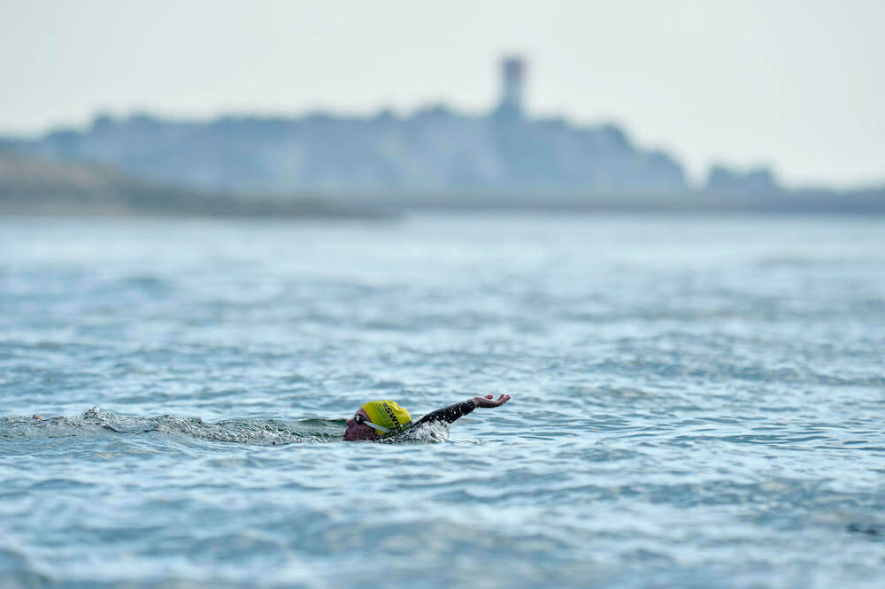 A swimmer does the backstroke with the town of Winthrop in the distance during the 2018 Swim Across America Boston Harbor open water swim on Friday July 13, 2018. Photo by Joseph Salvatore Prezioso