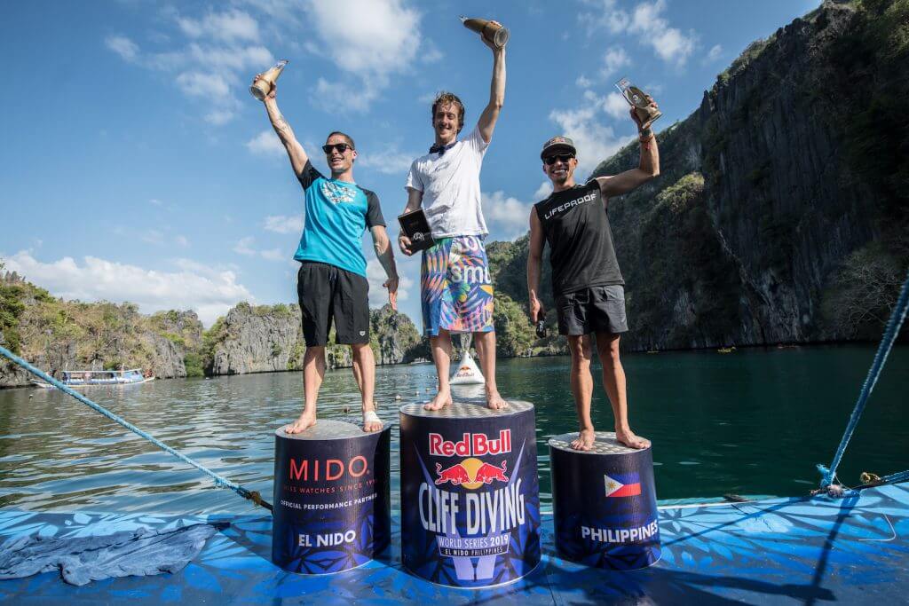 Constantin Popovici of Romania, Gary Hunt of the UK and Jonathan Paredes of Mexico celebrate on the podium at the Big Lagoon on Miniloc Island during the final competition day of the first stop of the Red Bull Cliff Diving World Series in Palawan, Philippines on April 13, 2019. // Romina Amato/Red Bull Content Pool // AP-1Z15215ZH1W11 // Usage for editorial use only // Please go to www.redbullcontentpool.com for further information. //