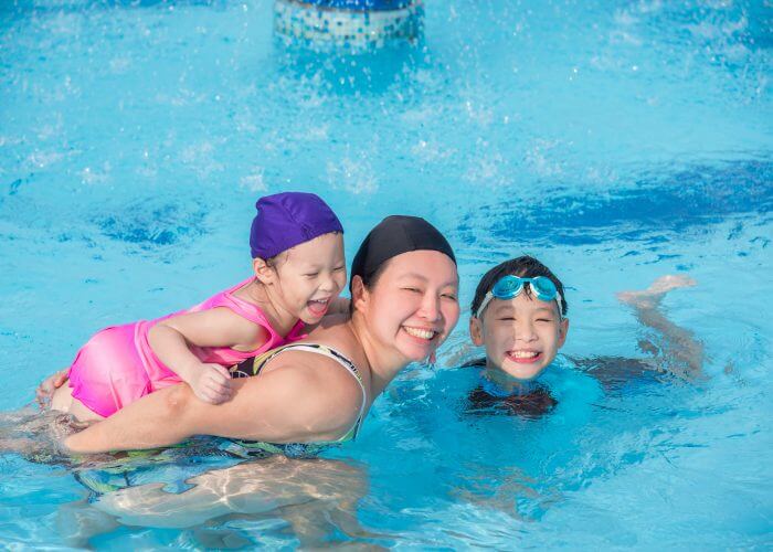 Asian mother and her children happy in swimming pool of a resort together in sunny day